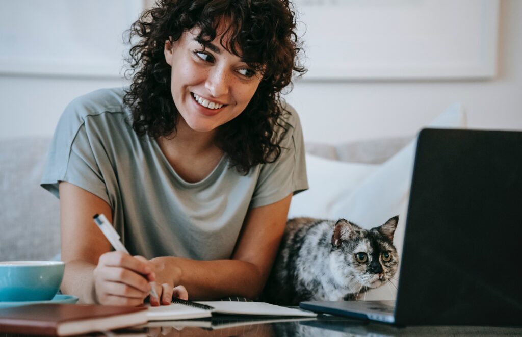 woman smiling at laptop with cat